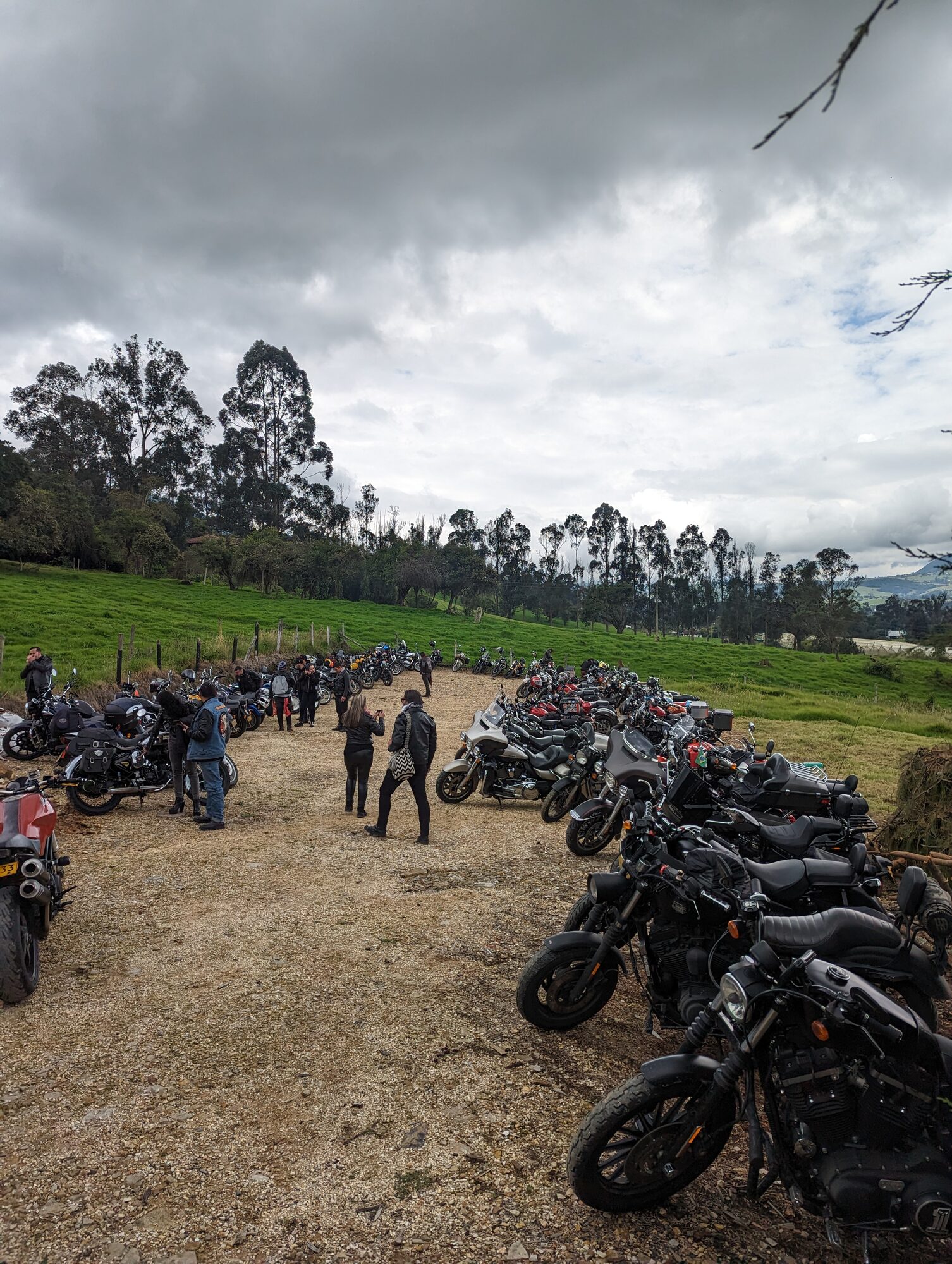Gran reunión de motos en zona de tierra y grava con campos verdes alrededor